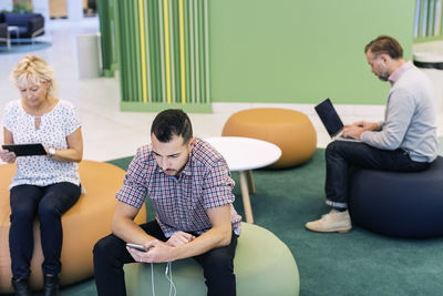 Businesspeople using technologies at lobby in modern office