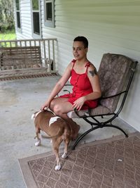 Young woman with dog sitting at porch