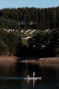 People on lake against trees