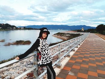 Portrait of woman standing by lake against sky