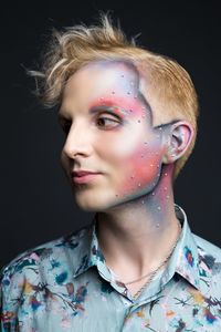 Close-up of young man with make-up against black background