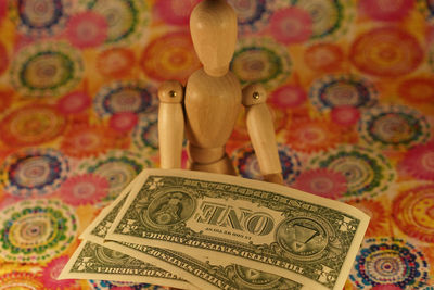 Wooden figurine with currencies on designed paper