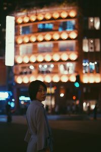 Portrait of man standing in illuminated city at night