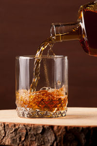 Whiskey glass on wooden table, brown background