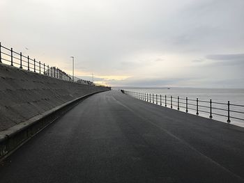 Road by sea against sky during sunset