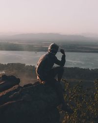 Man on rock against sky during sunset