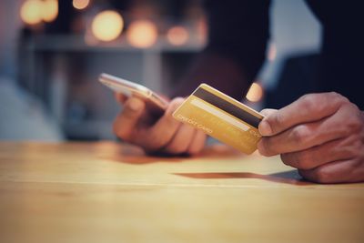 Close-up of hand holding smart phone on table