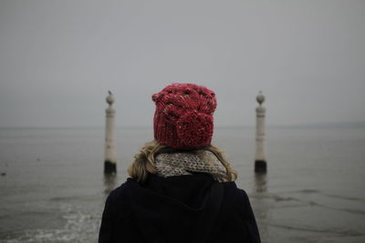 Rear view of woman wearing warm clothing while standing against sea