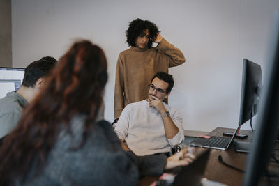 Multiracial female and male computer programmers discussing in startup company