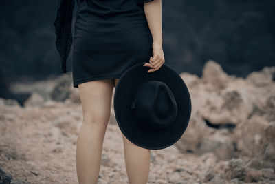 Midsection of woman holding hat while standing on land