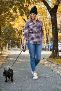 Full length of woman with dog standing against trees