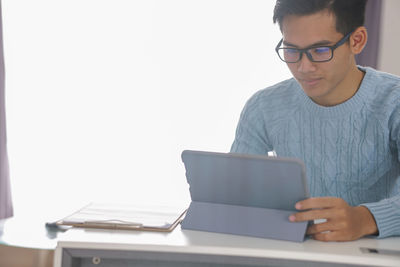 Man using mobile phone while sitting on table