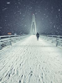 Rear view of man walking on snow in city