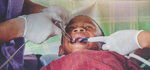 Cropped hands of dentist examining boy tooth in hospital