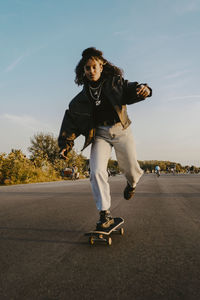 Portrait of cheerful woman skating on road in park