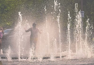 Silhouette man splashing water fountain