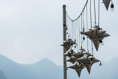 Low angle view of birds on cable against sky