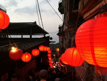 Illuminated lanterns hanging against orange sky