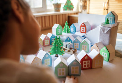 Origami advent calendar, paper craft. girl looking upon paper houses with number and paper tree