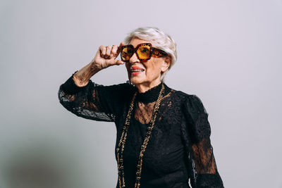 Portrait of young woman wearing sunglasses against white background