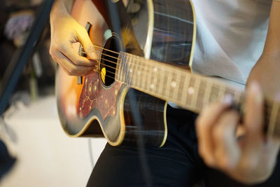 Midsection of man playing guitar