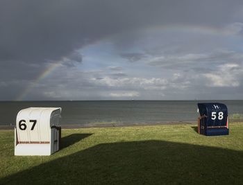 Information sign on field by sea against sky