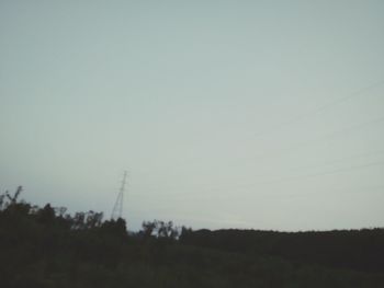 Electricity pylon on field against clear sky