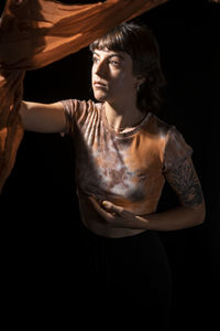 Portrait of woman standing against black background