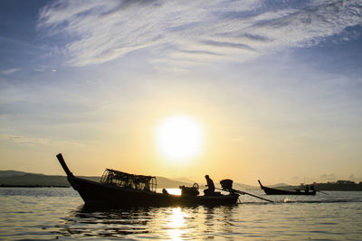 Silhouette boats in sea against sky during sunset