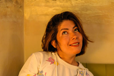 Portrait of smiling young woman against wall at home