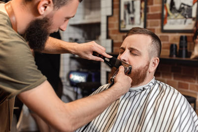 Barber trimming hair of customer