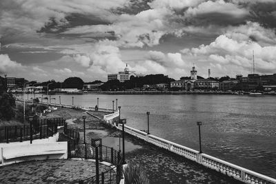 Bridge over river by buildings in city against sky