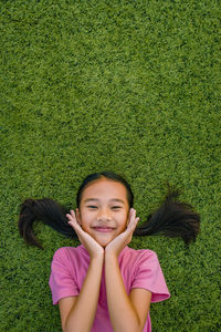 Portrait of smiling girl lying on grassy field