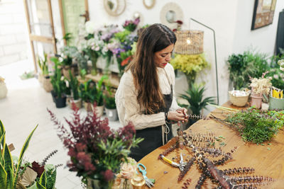 Saleswoman arranging leaves on workbench at floral shop