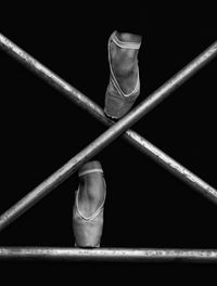 Low section of ballet dancer climbing on railing against black background