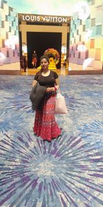 Woman looking away while standing against illuminated traditional clothing