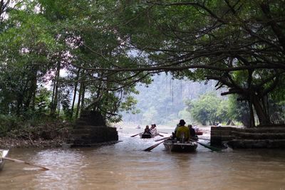 People sitting on riverbank in forest