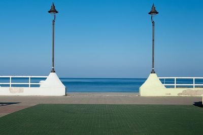 Street light by sea against clear sky