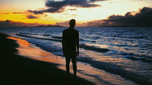 Rear view of silhouette man standing on beach