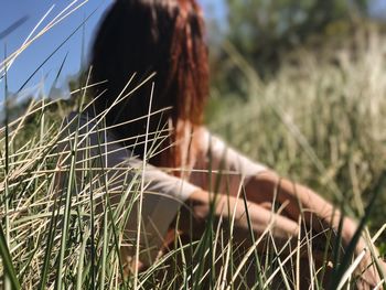 Woman sitting on grassy field during sunny day