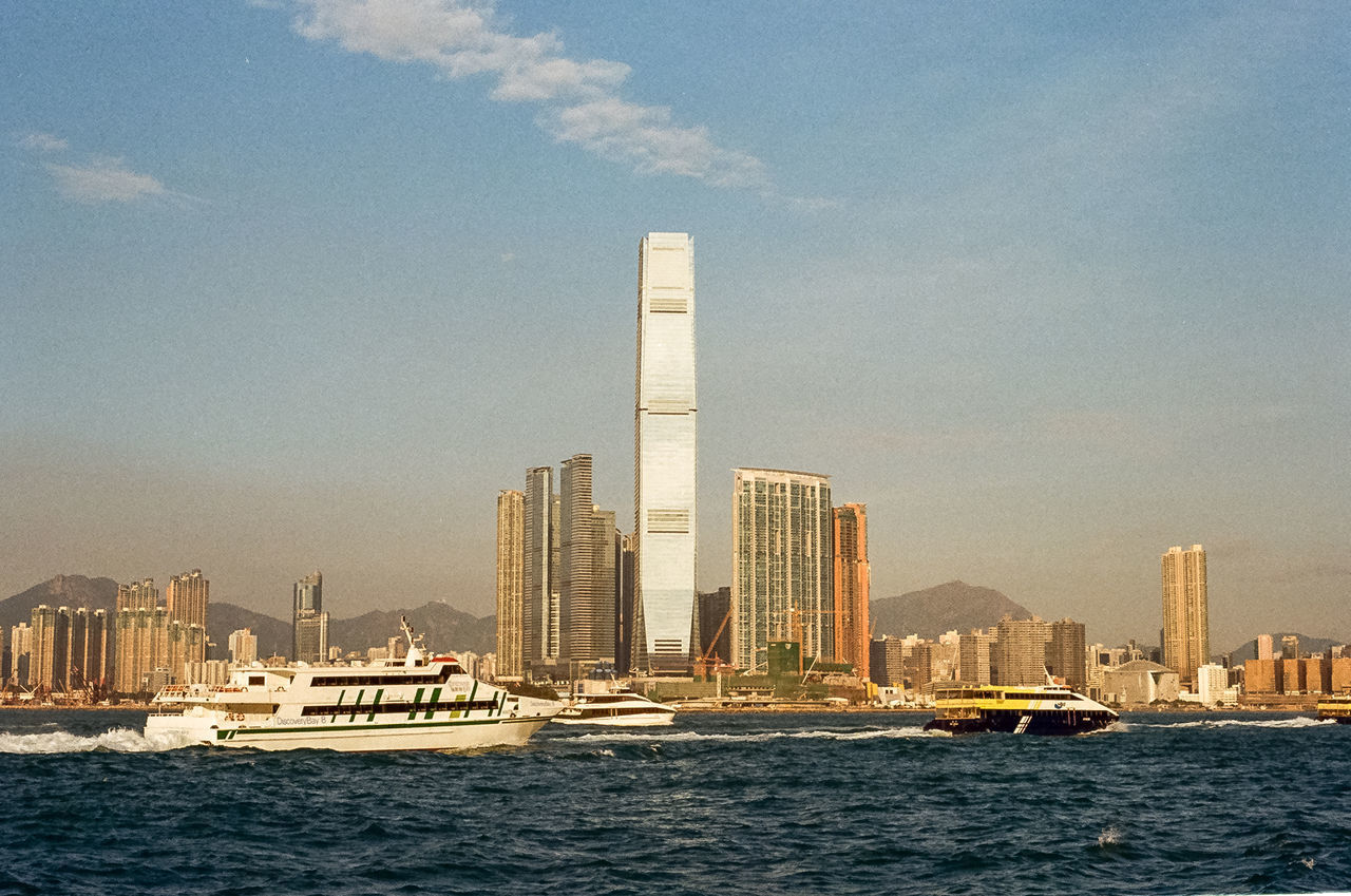 SEA BY MODERN BUILDINGS AGAINST SKY