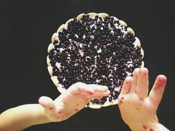 Close-up of hand holding ice cream cone against black background