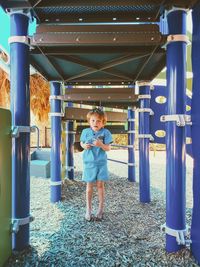 Full length of girl standing under playground equipment