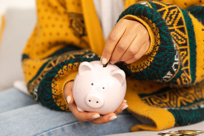 Midsection of woman holding piggy bank on table