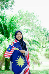 Muslim woman happy holding a malaysian flag. malaysia independence day.