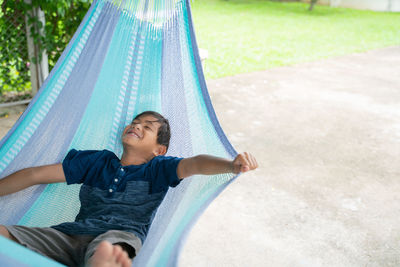 Smiling boy lying on hammock at park