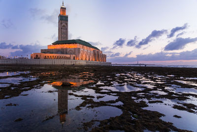 View of lighthouse by sea against sky during sunset