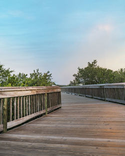 Wooden footbridge on footpath against sky