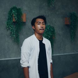 Portrait of young man standing against wall