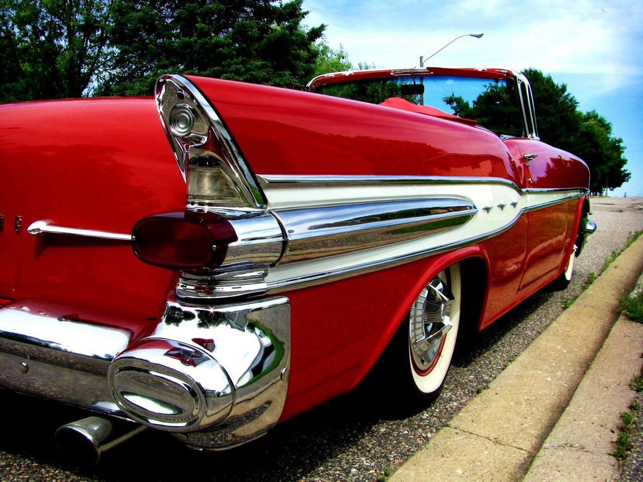 transportation, mode of transport, land vehicle, red, car, stationary, travel, nautical vessel, tree, sunlight, outdoors, day, no people, boat, part of, sky, parking, vintage car, wheel, street